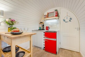 A compact kitchen with a wooden table, a red appliance, and a white door.