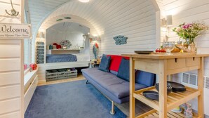 Ein gemütliches Zimmer mit einer Couch, einem kleinen Tisch mit Geschirr und einem Schild mit der Aufschrift 'Willkommen'.