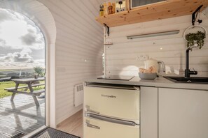 A compact kitchen with a built-in refrigerator, a sink, and a wooden countertop.