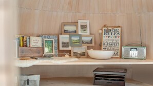 Une pièce chaleureuse avec une étagère en bois où sont exposés des livres, des photos encadrées, un bol, une radio et une petite boîte en bois.