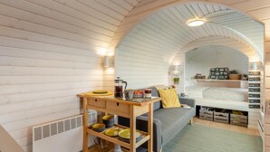 A cozy room with wooden walls, a sofa, a coffee table, and a bed with storage drawers underneath. - 1 Bed in Widegates (oc-j34234) (Deviock)