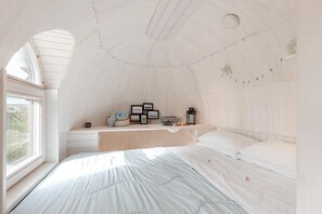 A cozy, tent-like bedroom with a bed, a small table, and framed pictures.