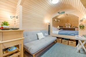 A cozy interior with a sofa, a small table with a plant, and a bed with a wooden headboard.