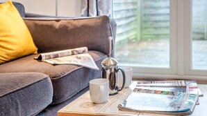 A cozy living room with a sofa, a coffee pot, a mug, and a table with magazines. - 1 Bed in Hindhead (oc-w34256) (Haslemere)