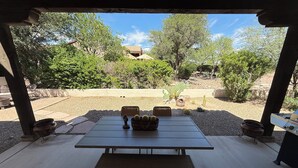 A covered patio with a table and benches, surrounded by desert landscaping and trees. - Luxury Vacation Rental in historic Tubac, Arizona --Come see Southern Arizona! (Tubac)