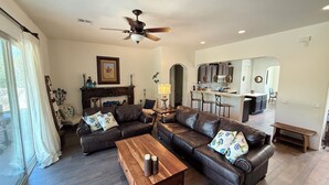 A spacious living room with a fireplace, leather sofas, a wooden coffee table, and a ceiling fan. - Luxury Vacation Rental in historic Tubac, Arizona --Come see Southern Arizona! (Tubac)