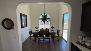 A dining area with a wooden table and chairs, a star-shaped chandelier, and a window with a view of the outdoors. - Luxury Vacation Rental in historic Tubac, Arizona --Come see Southern Arizona! (Tubac)