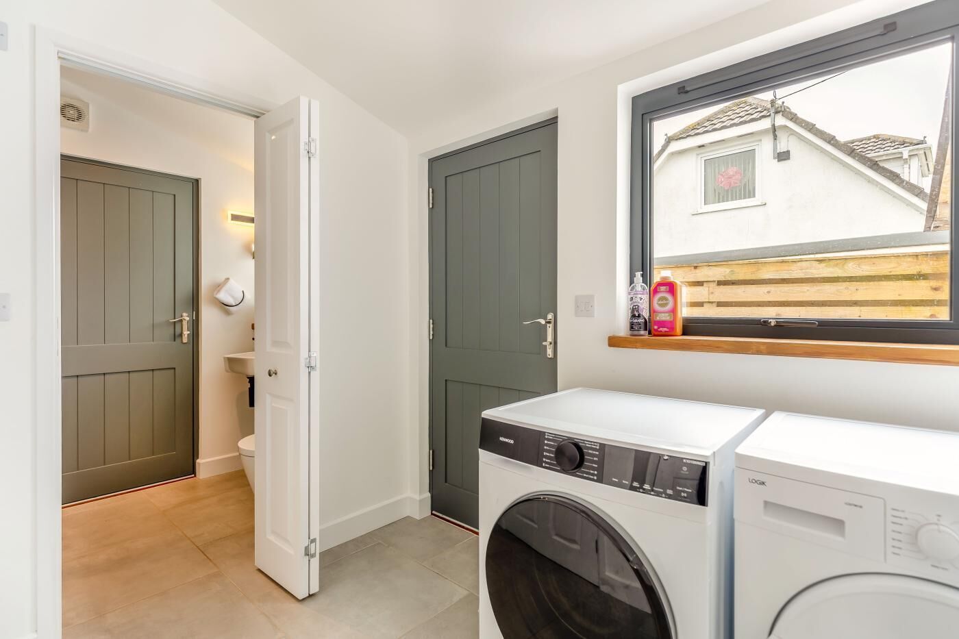 A laundry area with a washing machine, a dryer, and a window with a view of a building.
