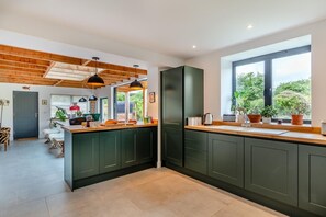 Een moderne keuken met donkergroene kastjes, een houten plafond en een groot raam.
