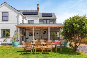 Een tweelaags huis met een overdekte patio, zonnepanelen en een verzorgde tuin.
