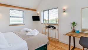 Une chambre à coucher avec un lit, un bureau, une chaise, une télévision et une fenêtre.