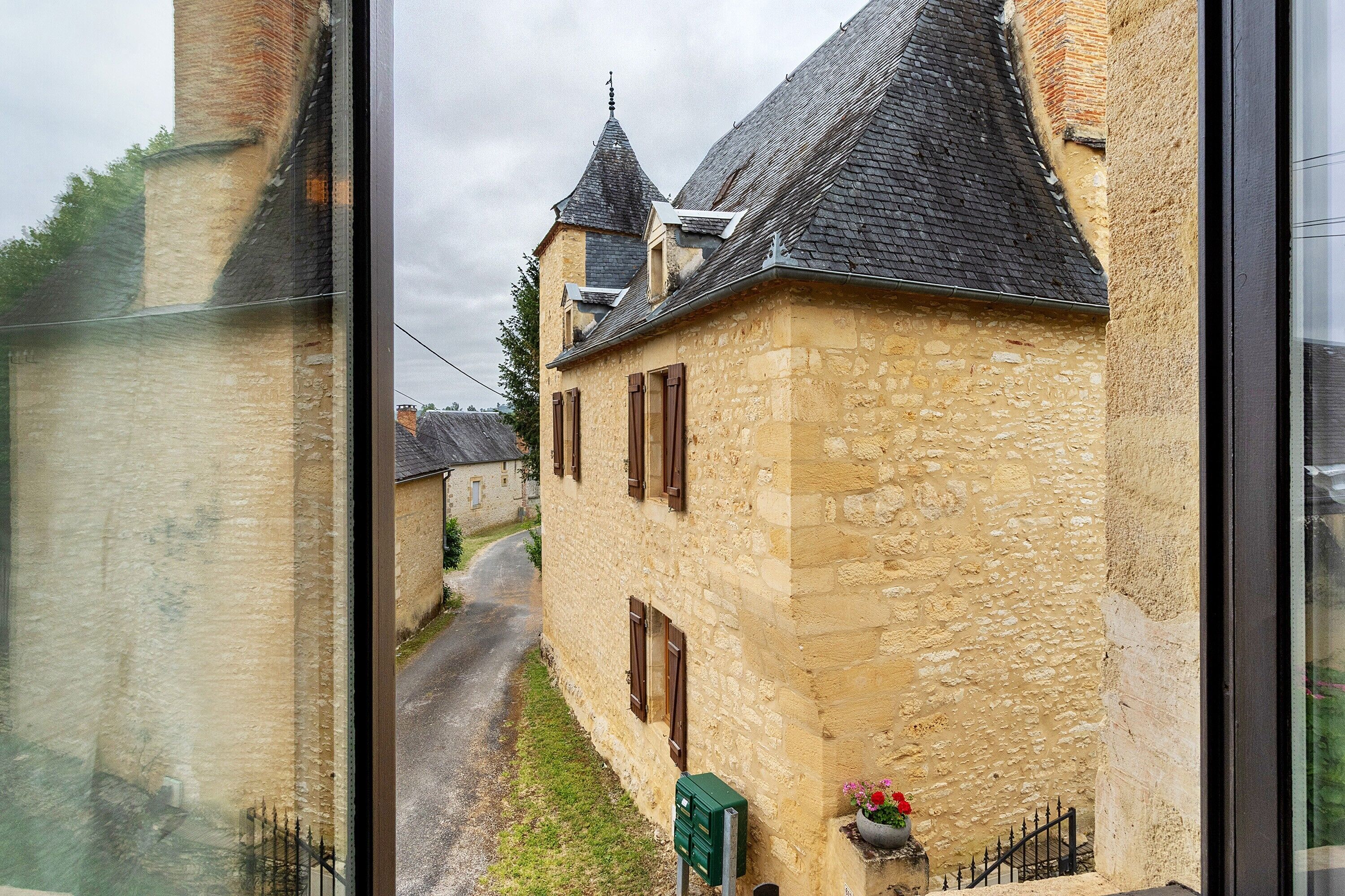 A stone building with a narrow street, a chimney, and a small garden with flowers.