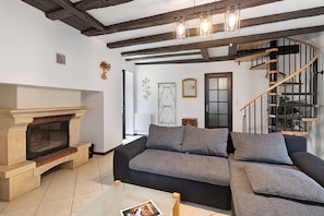 Una sala de estar con chimenea, una escalera curva y un sofá.