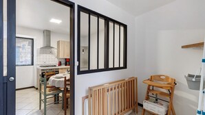 Una cocina con mesa de comedor, sillas, una cuna de madera y cambiador para bebés.