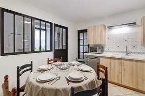 Een eethoek met een ronde tafel voor zes personen, omringd door houten stoelen.