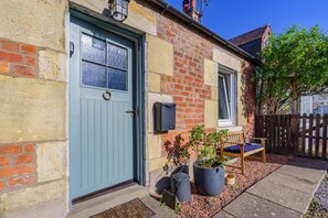 A two-story house with a blue door, a brick exterior, and a wooden bench outside. - 1 Bed in Errol (oc-s33022) (Errol)
