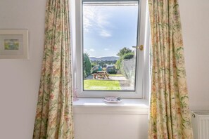 A window with floral curtains, a view of a garden, and a framed picture on the wall. - 1 Bed in Errol (oc-s33022) (Errol)
