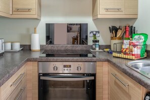 A modern kitchen with a built-in oven, a stainless steel range, and wooden cabinets.
