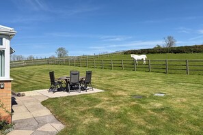 A patio with outdoor furniture, a white horse in the background, and a fenced field. - 2 Bed in Harbury (oc-b34221) (Harbury)
