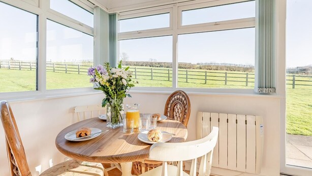 Una mesa de desayuno con vistas a un campo verde y una valla.