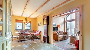 Un amplio salón con una mesa de comedor, un sofá y una chimenea.