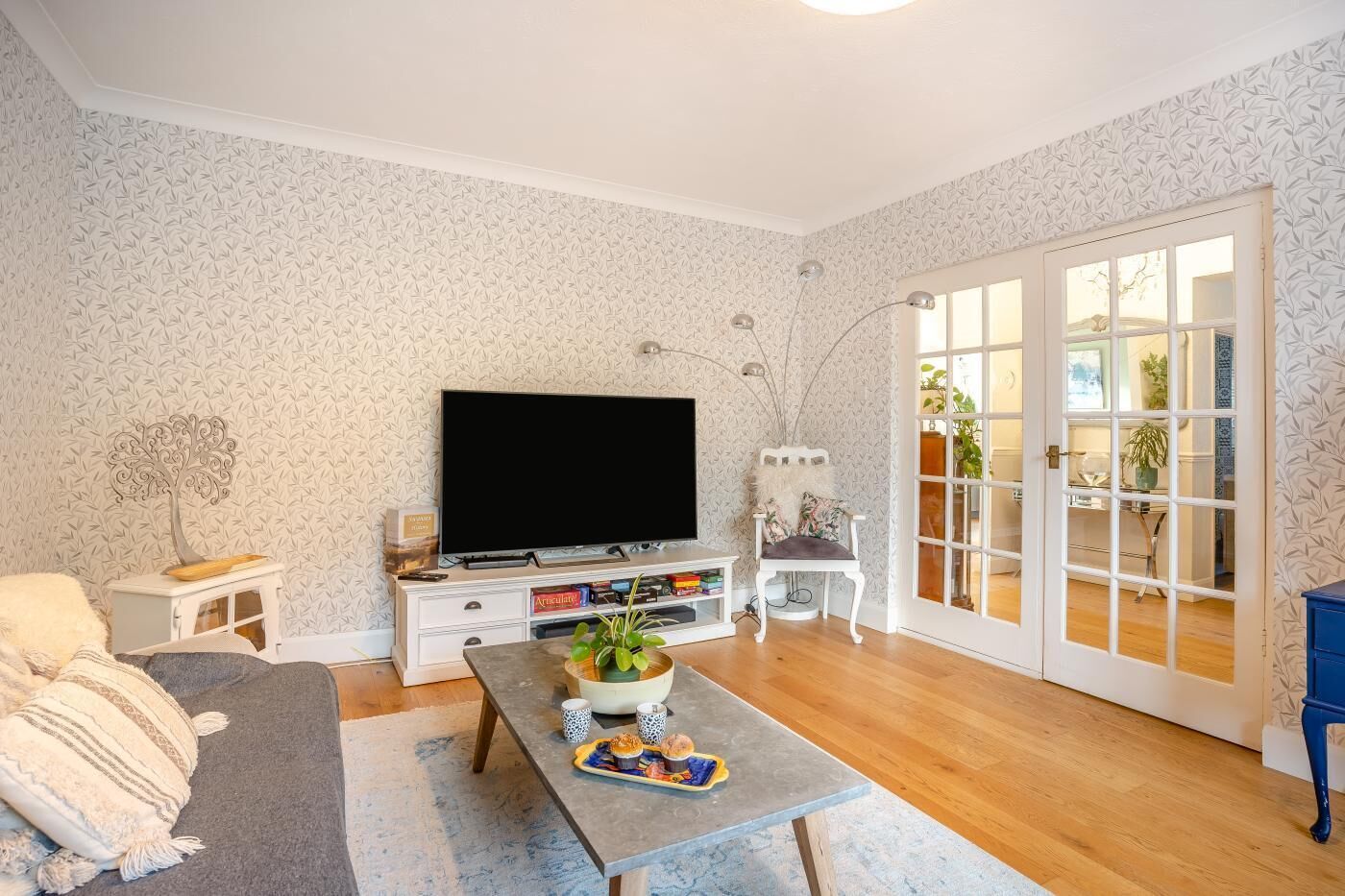 Ein Wohnzimmer mit Flachbildfernseher, Couch, Sessel und einem Couchtisch mit Obstschale.
