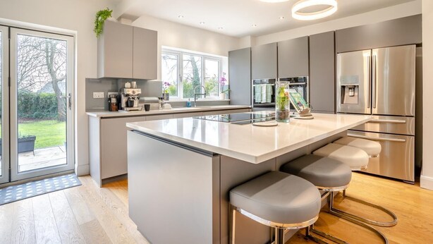 Una cucina moderna con una grande isola, elettrodomestici in acciaio inossidabile e vista sull'esterno.