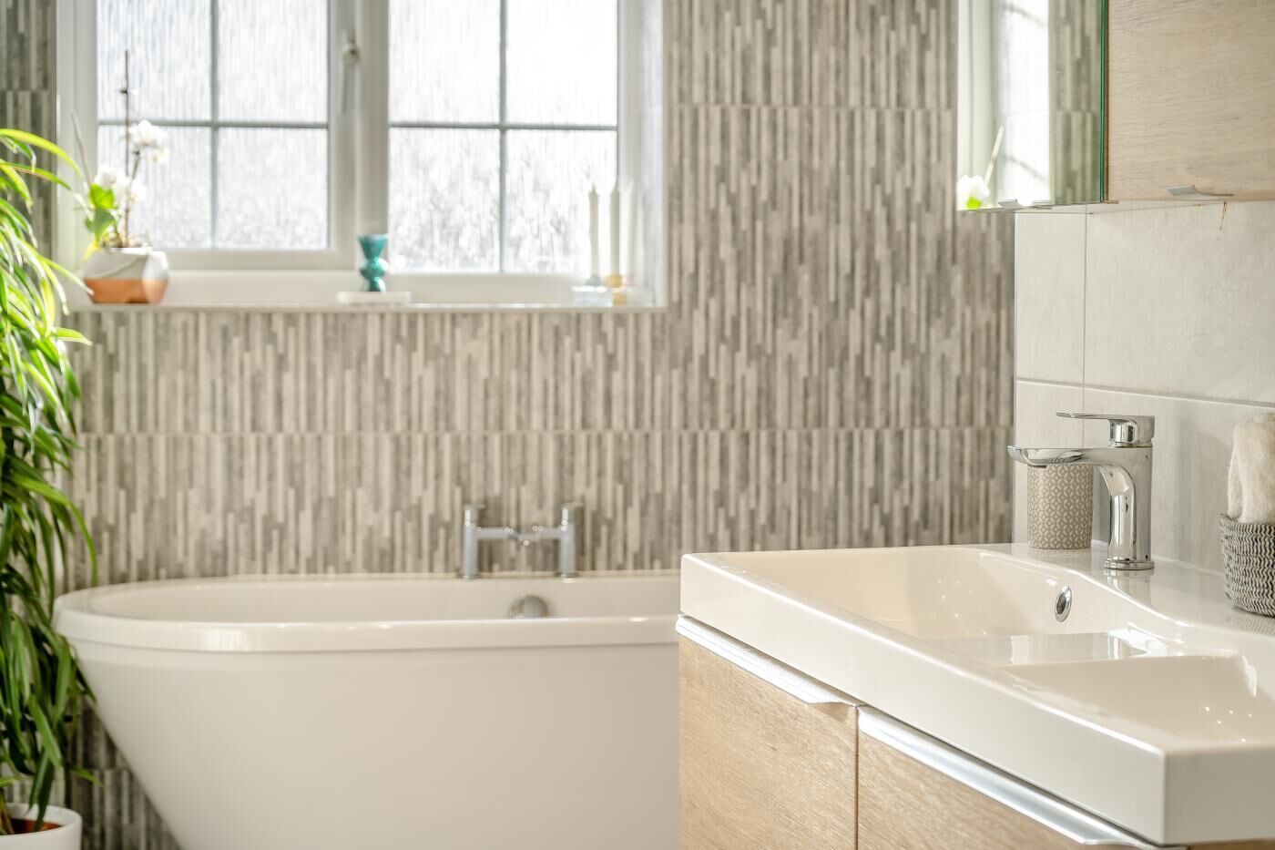 Un baño moderno con una bañera independiente, un lavamanos grande y un ventanal con vistas al exterior.