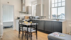 Una cocina moderna con armarios grises, una isla central con taburetes altos y un ventanal con vistas a casas.