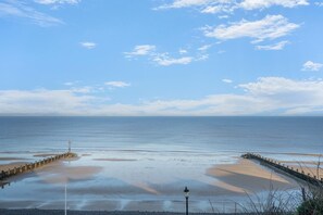 Une vue sur la côte, avec une mer calme, une plage de sable et une jetée en pierre.