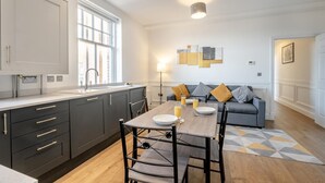 Una cocina moderna con armarios oscuros, un ventanal grande y un comedor con una mesa dispuesta para dos.