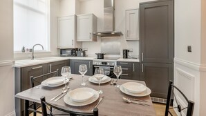 Une cuisine moderne avec une table à manger pour quatre personnes, équipée d’une cuisinière, d’un four à micro-ondes et d’un évier.