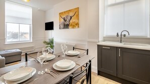 Une cuisine moderne avec un coin repas, une grande fenêtre et un téléviseur fixé au mur.