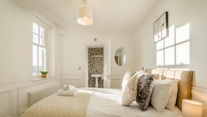 Een hotelkamer met een groot bed, een nachtkastje met een lamp, een raam met uitzicht en een badkamer door een open deur.