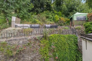A garden with a stone wall, a metal fence, and a green tent. - 7 Bed in Matlock Bath (oc-n34368) (Matlock Bath)