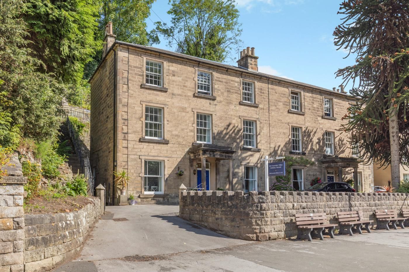 A stone building with multiple windows, a blue door, and a sign indicating it is a hotel.