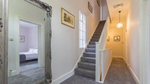 Ein Flur mit Treppe, einem großen Spiegel und einem Bett im Hintergrund.