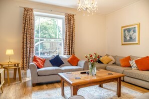 Ein Wohnzimmer mit einer Couch, einem Couchtisch, einer Lampe und einem Blumenstrauß.
