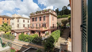 A multi-story building with balconies, a staircase, and surrounding greenery. - Rental in Rome Karan's Suite Apartment (Rome)