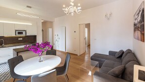 A modern living room with a dining table, a sofa, and a kitchen in the background. - Rental in Rome Karan's Suite Apartment (Rome)