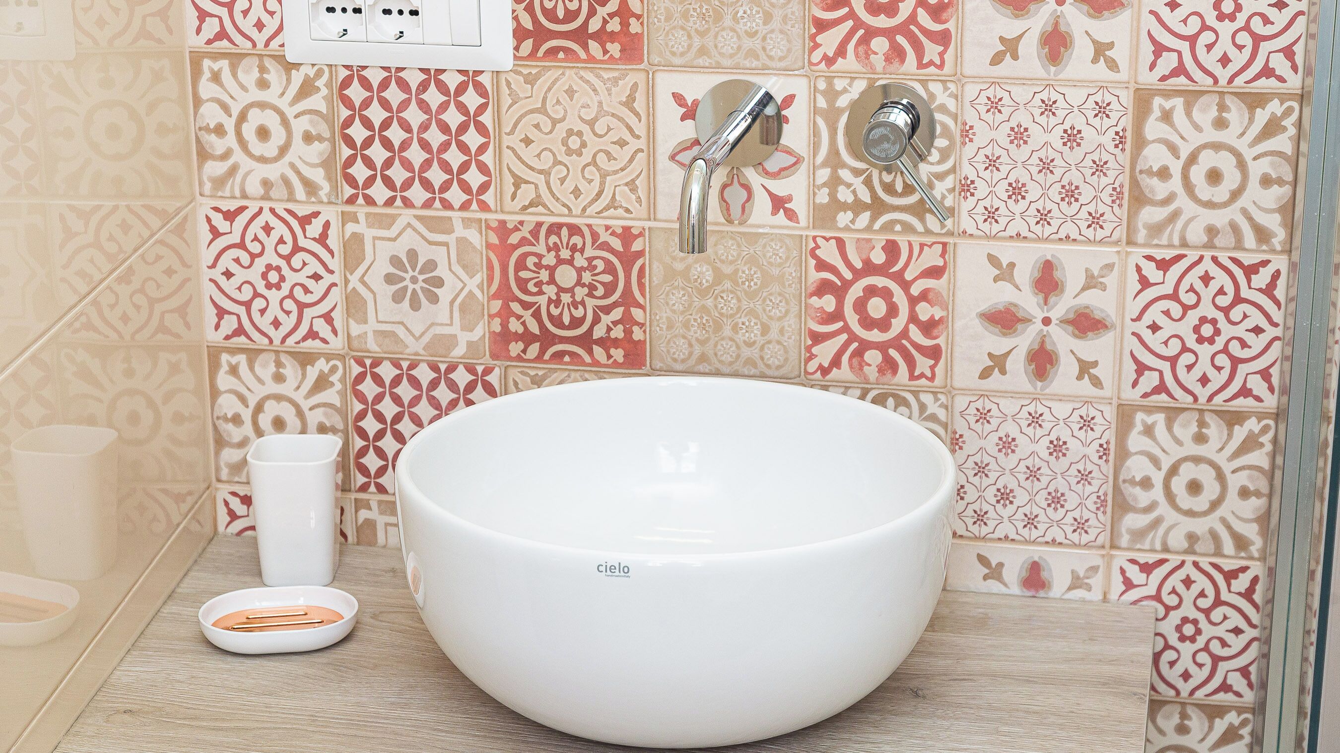 A bathroom with a white sink, a cup, and a soap dish.