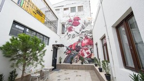 A narrow courtyard with a pomegranate mural, outdoor seating, and potted plants. - Molokan Inn Hotel (Baku)