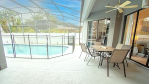 Un'area esterna coperta con piscina, posti a sedere e una ventola a soffitto.