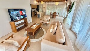 Een moderne woonkamer met een televisie, bank, stoelen en een eethoek.