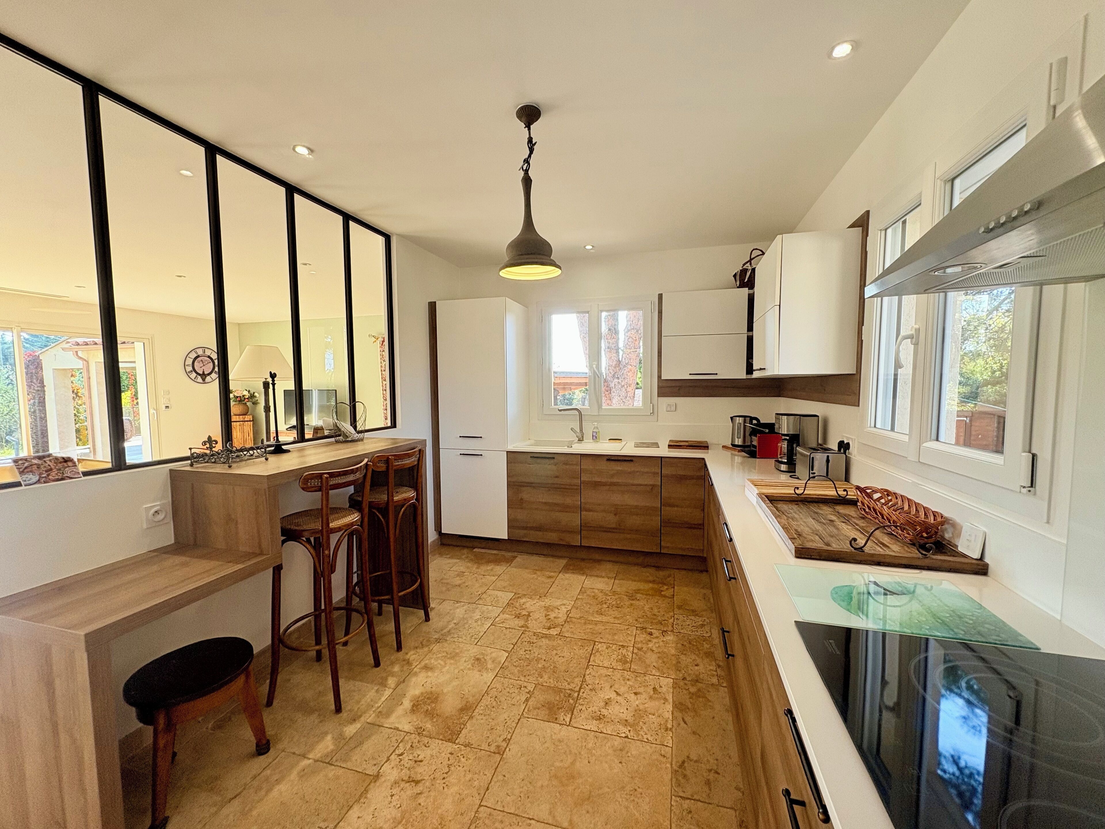 Une cuisine moderne avec un plan de travail en bois, des tabourets de bar et une grande fenêtre.