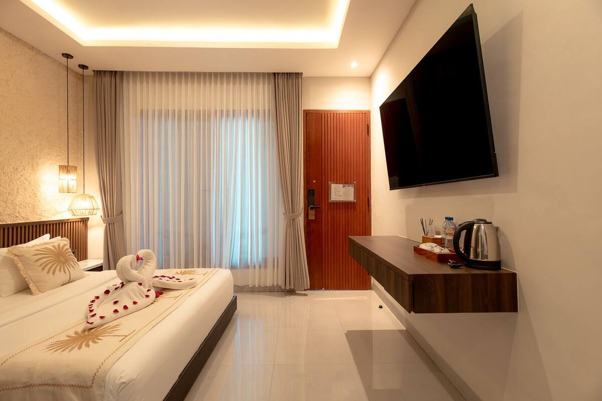 Camera d'albergo con un letto, una televisione, una scrivania in legno e una porta.