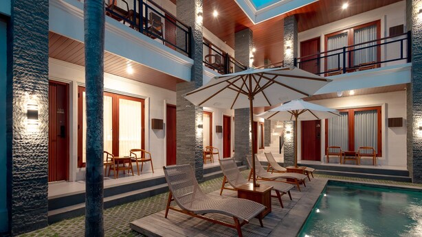 Ein mehrstöckiges Hotel mit Poolbereich, Außenbereich zum Sitzen und einer Treppe.