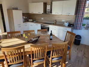 A modern kitchen with white cabinets, a wooden dining table, and chairs. - Holiday Home Kranichnest with Lake View, Private Terrace, Sauna & Wi-Fi (Breege)