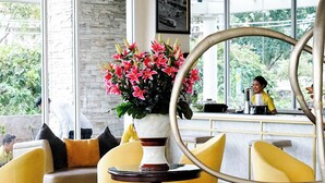 Een modern interieur met gele stoelen, een marmeren tafel en een grote spiegel.