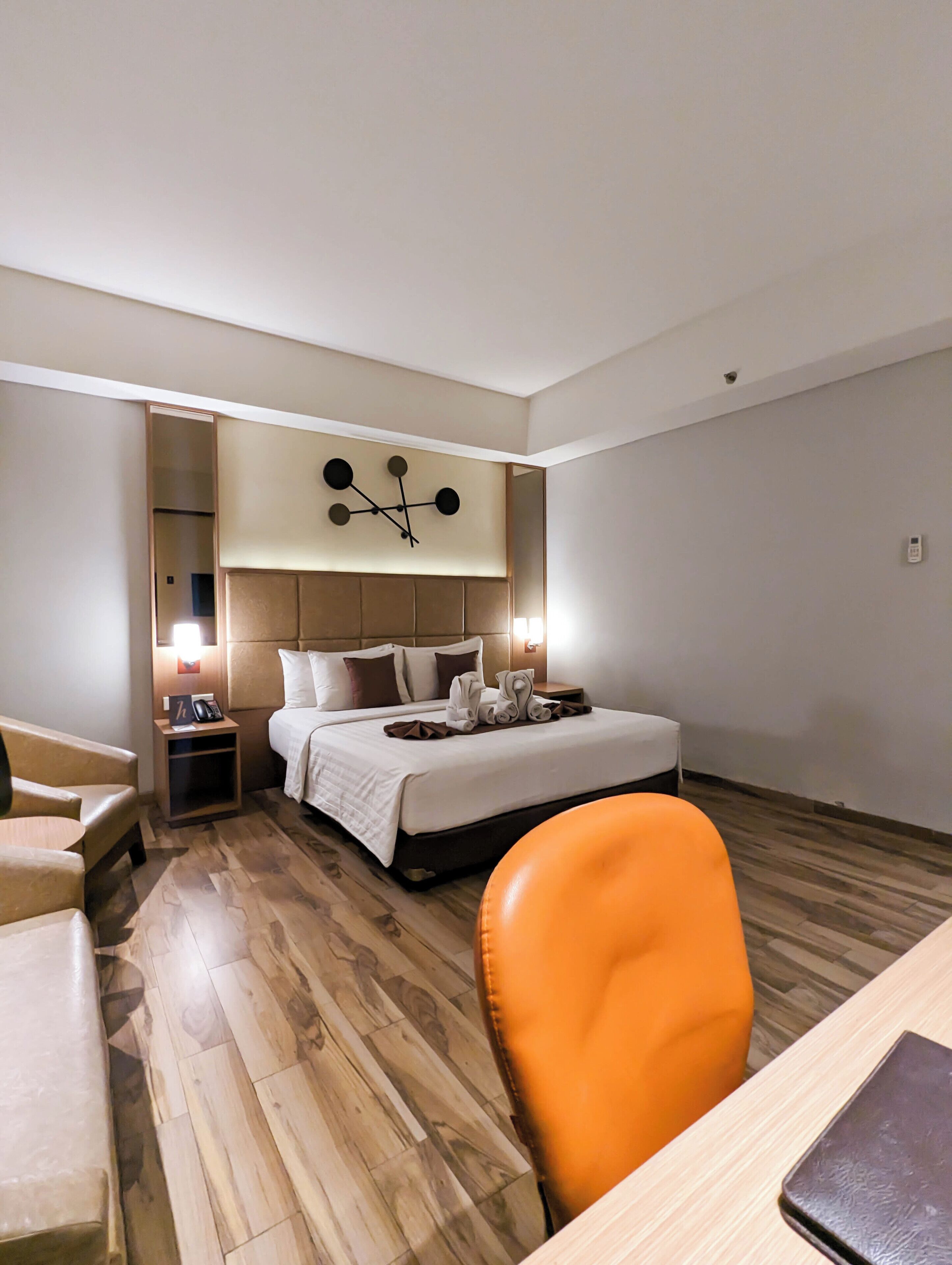 A hotel room with a bed, a desk, a chair, and a mirror.